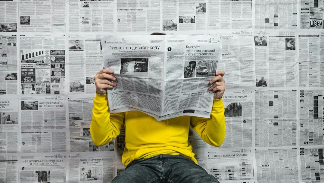 a person sitting on the floor reading a newspaper a person sitting on the floor reading a newspaper