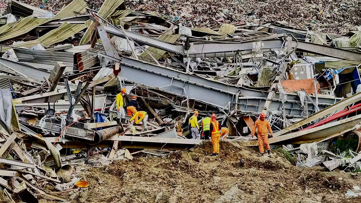 Rescuers in bright orange and yellow safety gear navigate a massive debris field of twisted gray steel beams, corrugated metal sheets, and piles of garbage following a landfill collapse in Cebu City