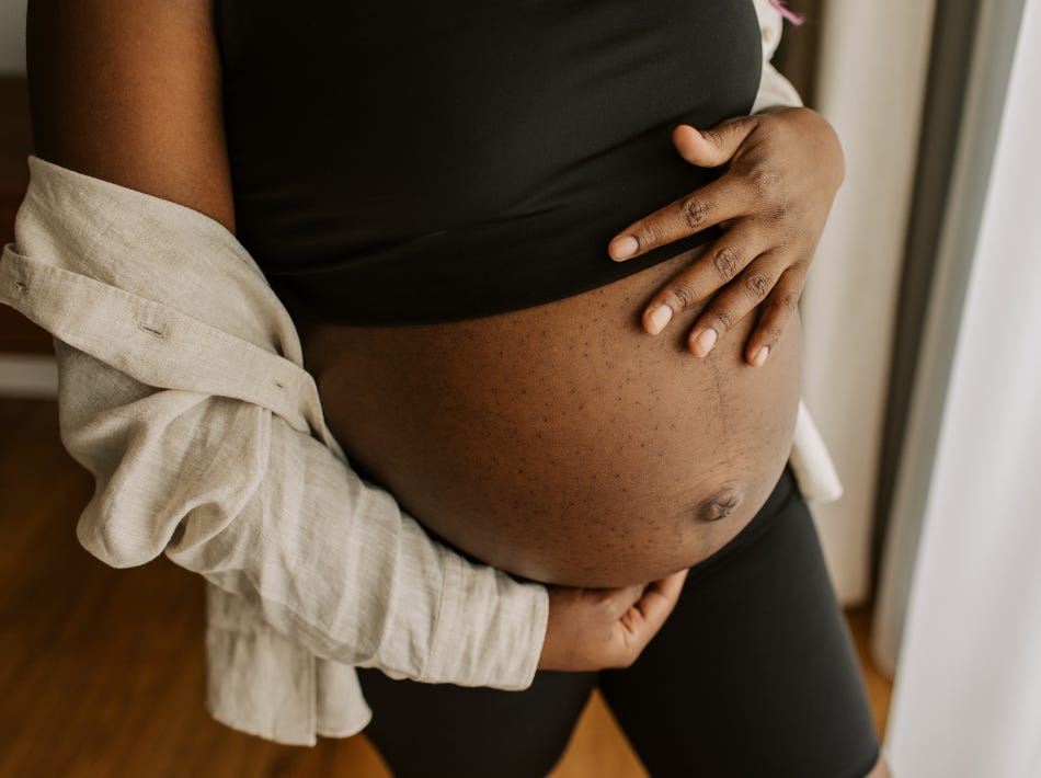 Black woman holding pregnant belly- third trimester abortion