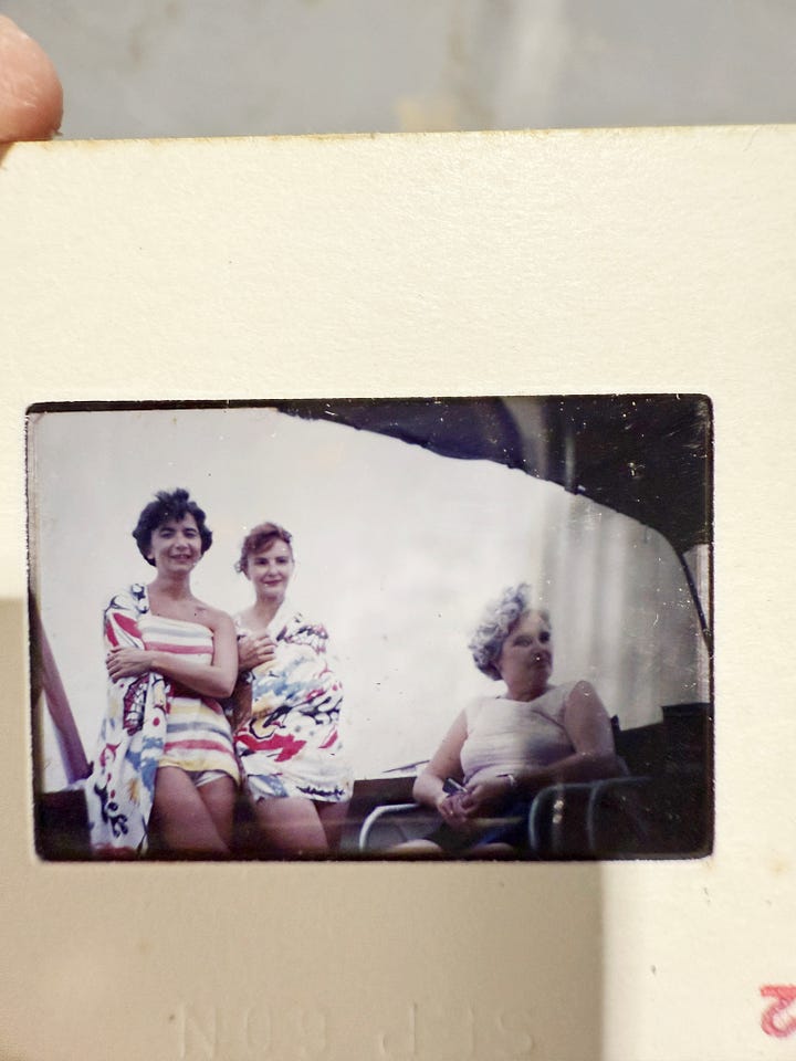 Collection of vintage Kodak slides showing various Caribbean vacation scenes including boats, people on docks, and sailing, plus a black vintage slide viewer device in a shopping cart