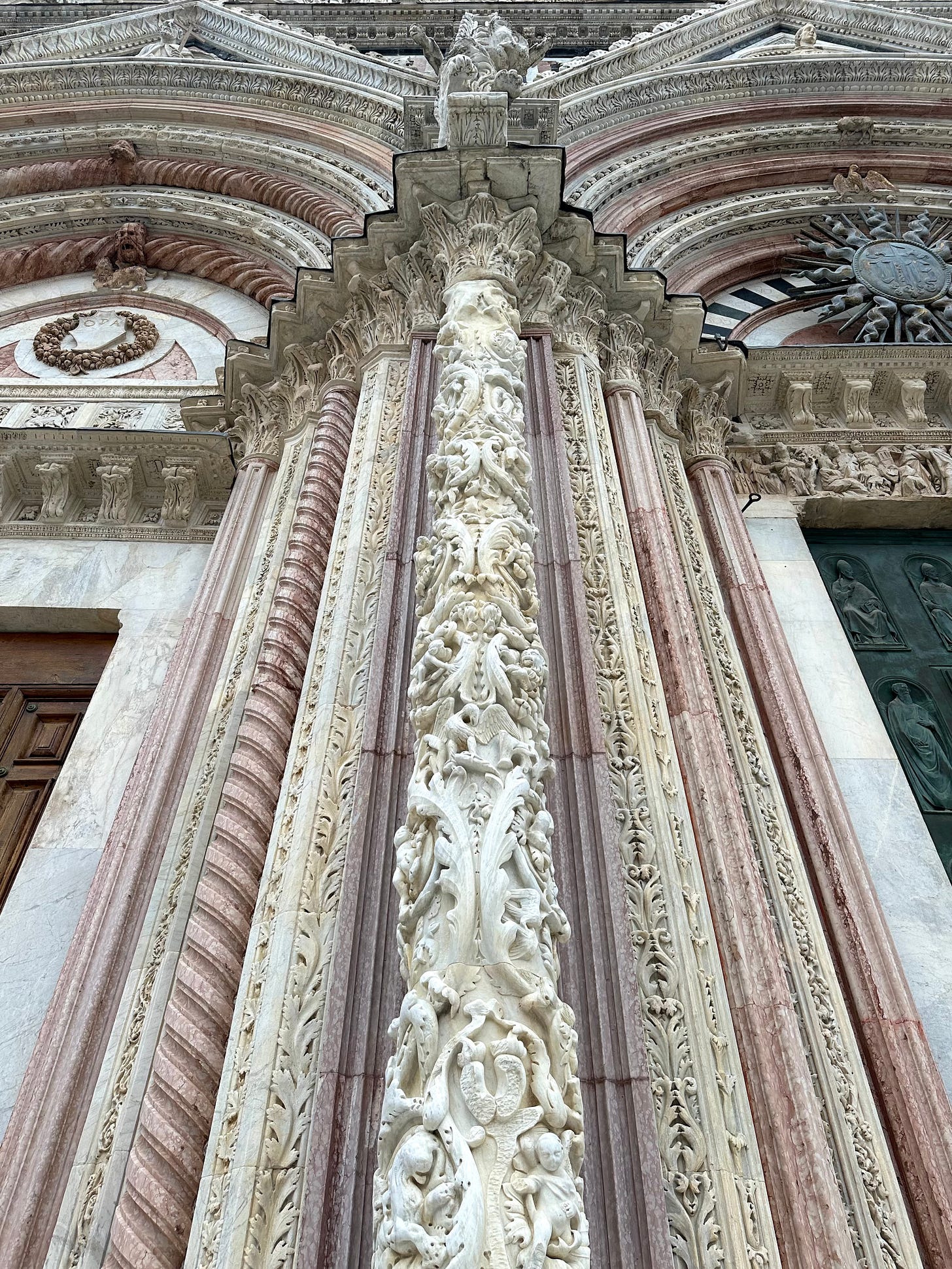 An ornately carved pillar on the exterior of Siena cathedral in Tuscany, Italy. Taken from a low wattage point, the column bisects the photo in a straight vertical line.