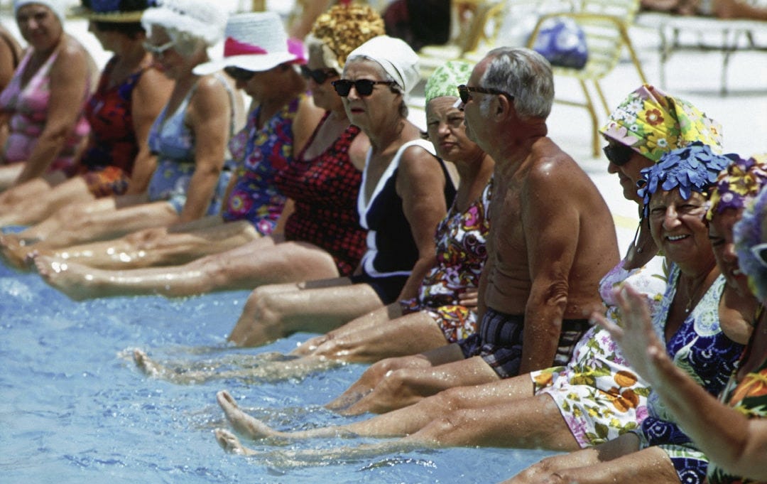 a group of people sitting next to each other in a swimming pool a group of people sitting next to each other in a swimming pool