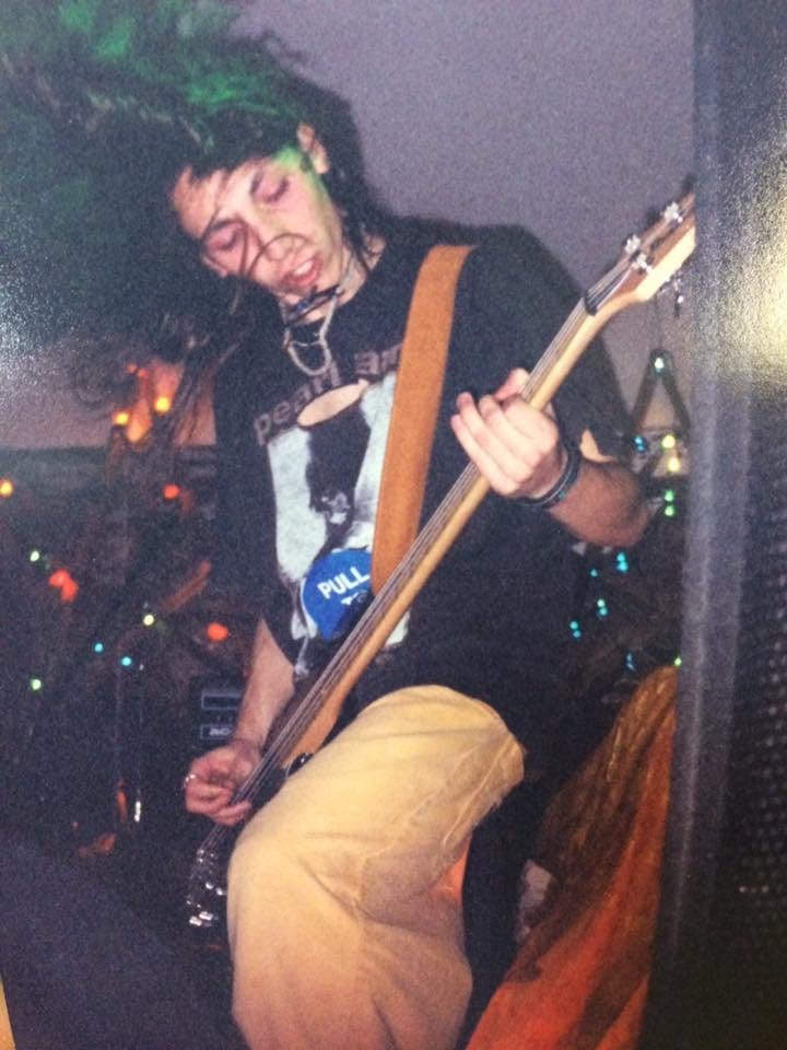A young Ira thrashes his long hair while playing bass guitar in a Pearl Jam t-shirt. A young Ira thrashes his long hair while playing bass guitar in a Pearl Jam t-shirt.