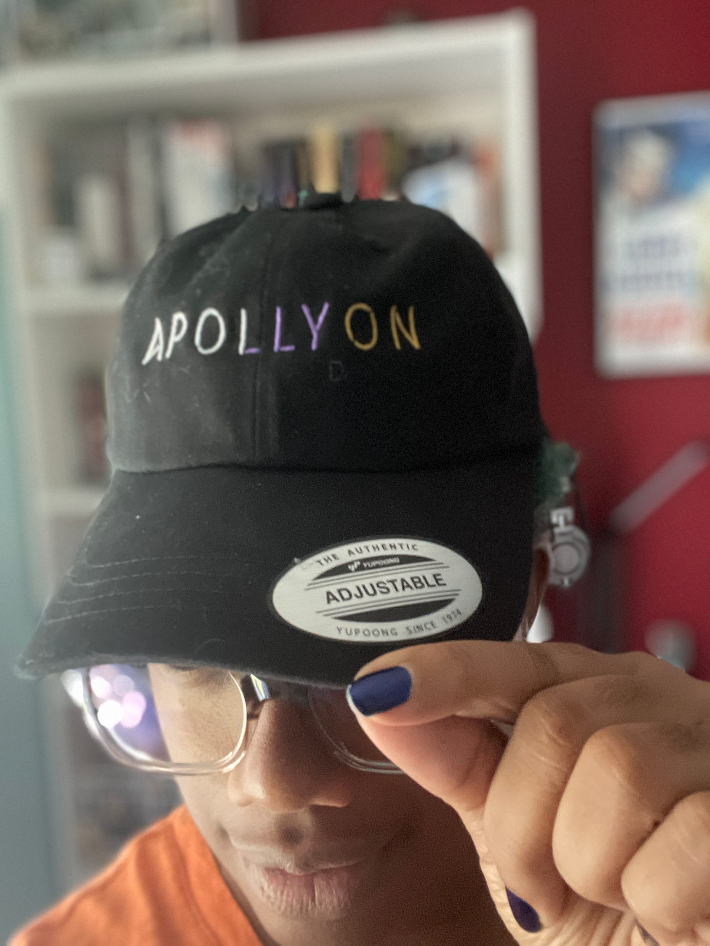 A black baseball cap with Apollyon in white, purple, and orange thread