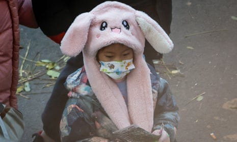 A child in Beijing wearing a face mask and a pink winter hat A child in Beijing wearing a face mask and a pink winter hat
