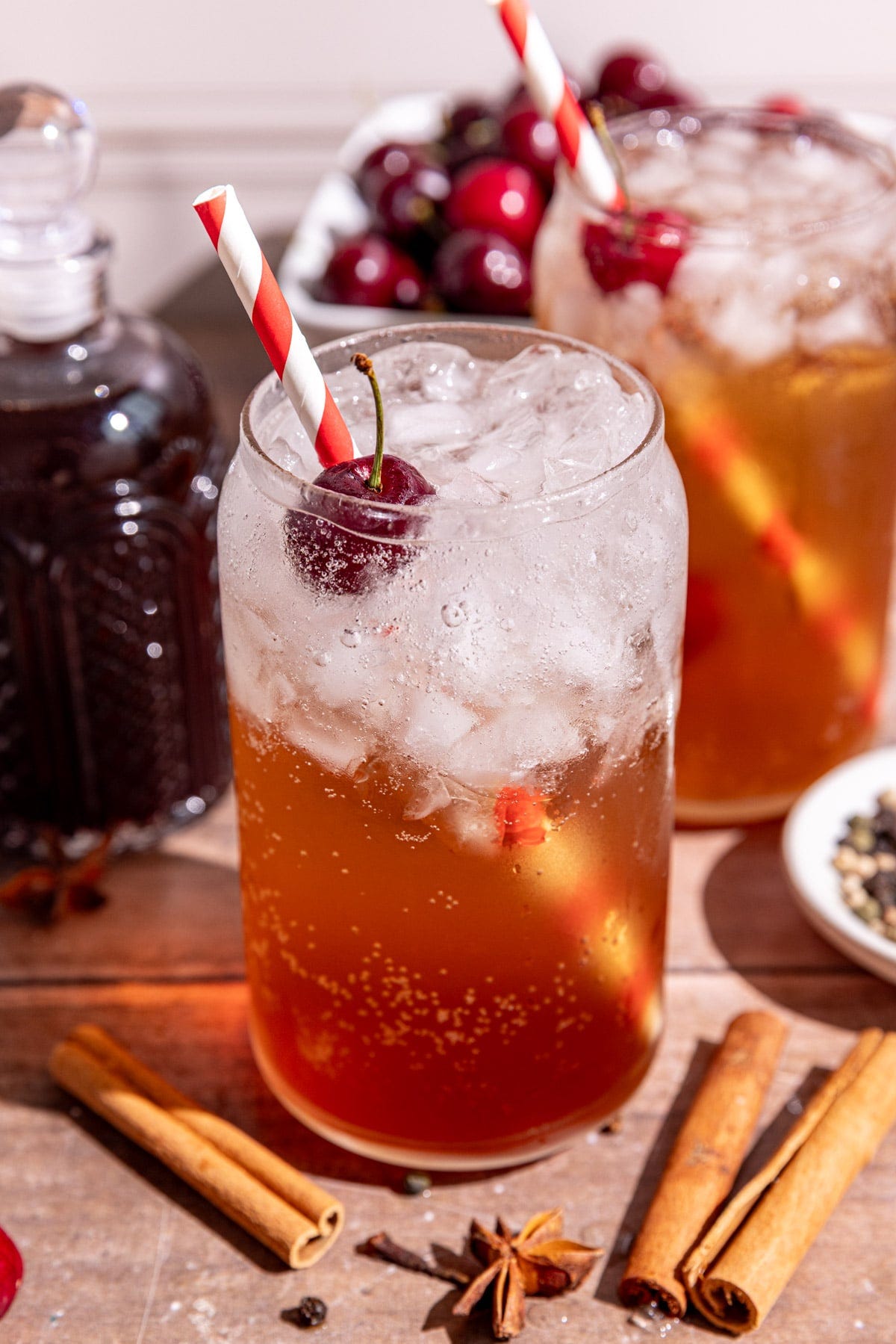 A soda glass of homemade Dr. Pepper with a cherry garnish and red & white striped straw. A soda glass of homemade Dr. Pepper with a cherry garnish and red & white striped straw.