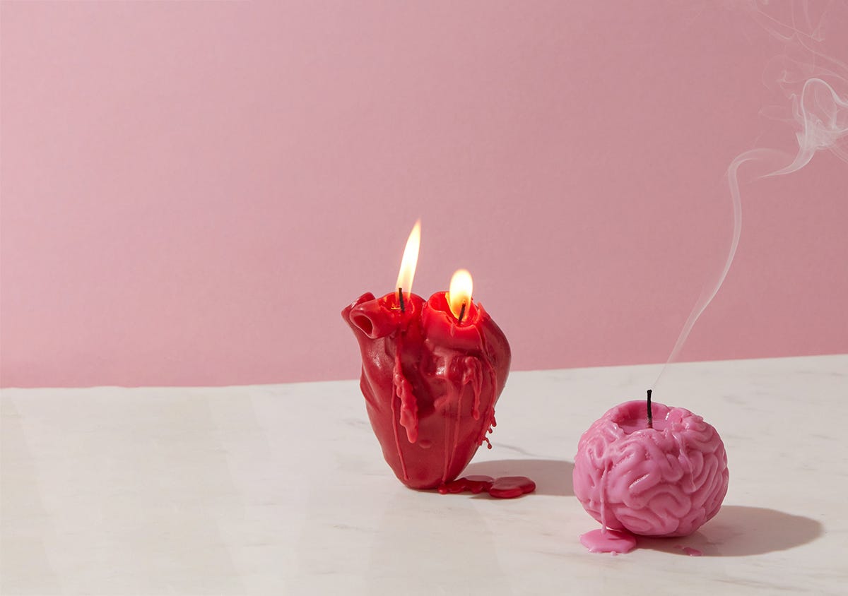 Deux bougies : l'une en forme de coeur (allumée) et l'autre en forme de cerveau (juste éteinte)