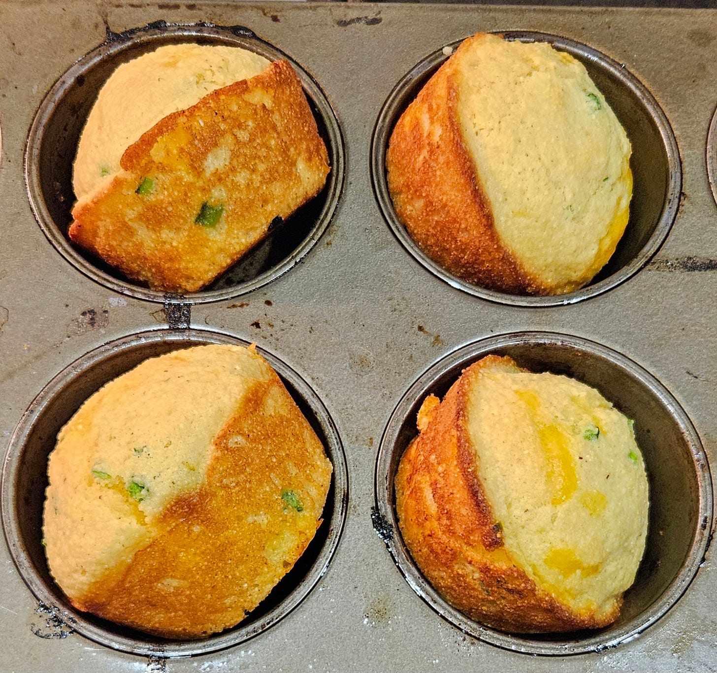 Four jalapeño cheddar corn bread muffin in the muffin tin