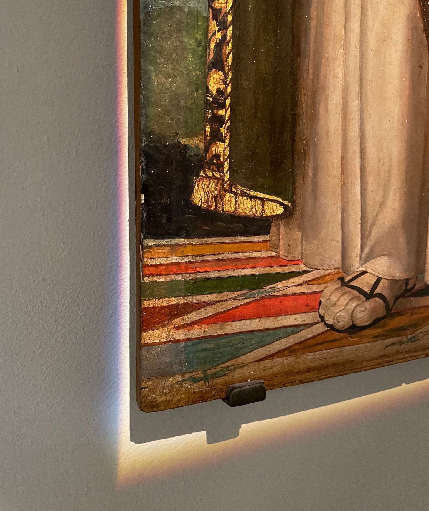 A painting of a foot on a wall with a rainbow reflection on the wall behind it