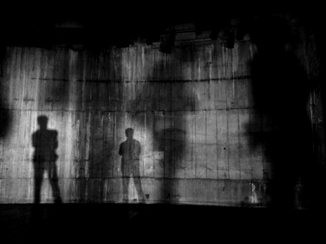 silhouette of man standing near wall on dark area silhouette of man standing near wall on dark area