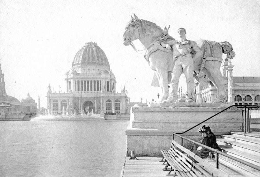 People sit on steps along the a lagoon beneath a sculpture of a draft horse and teamster.