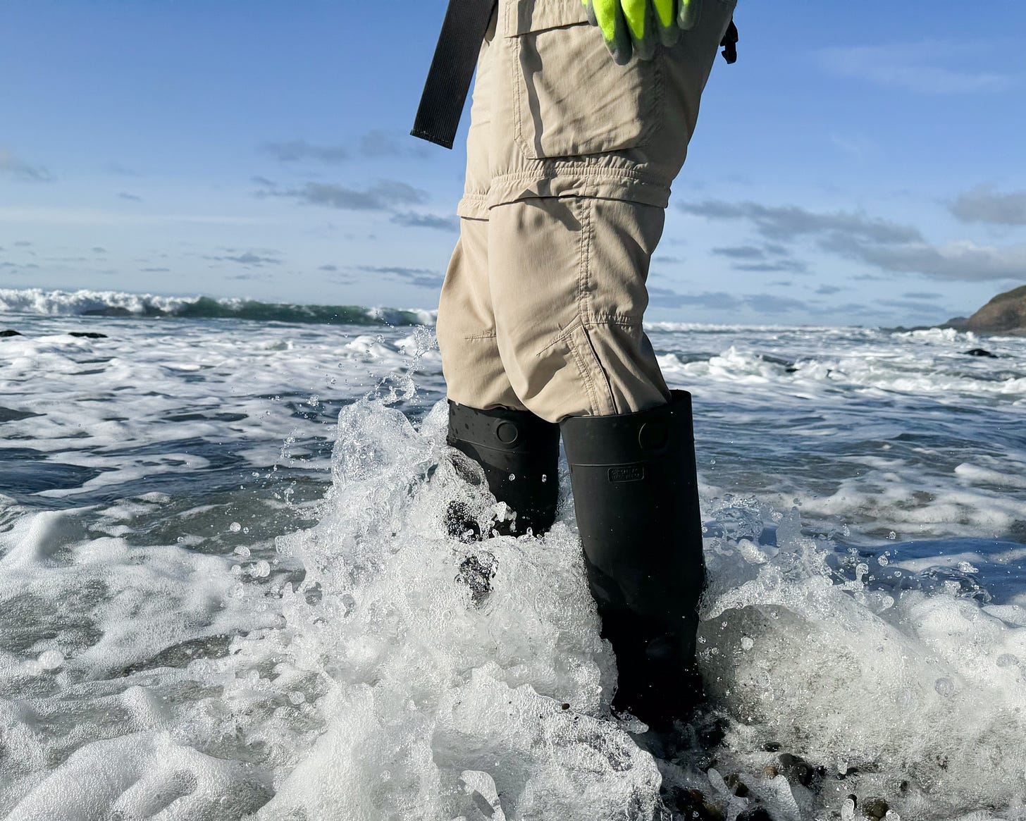 Someone standing in the tide while wearing a pair of hightop pvc boots.