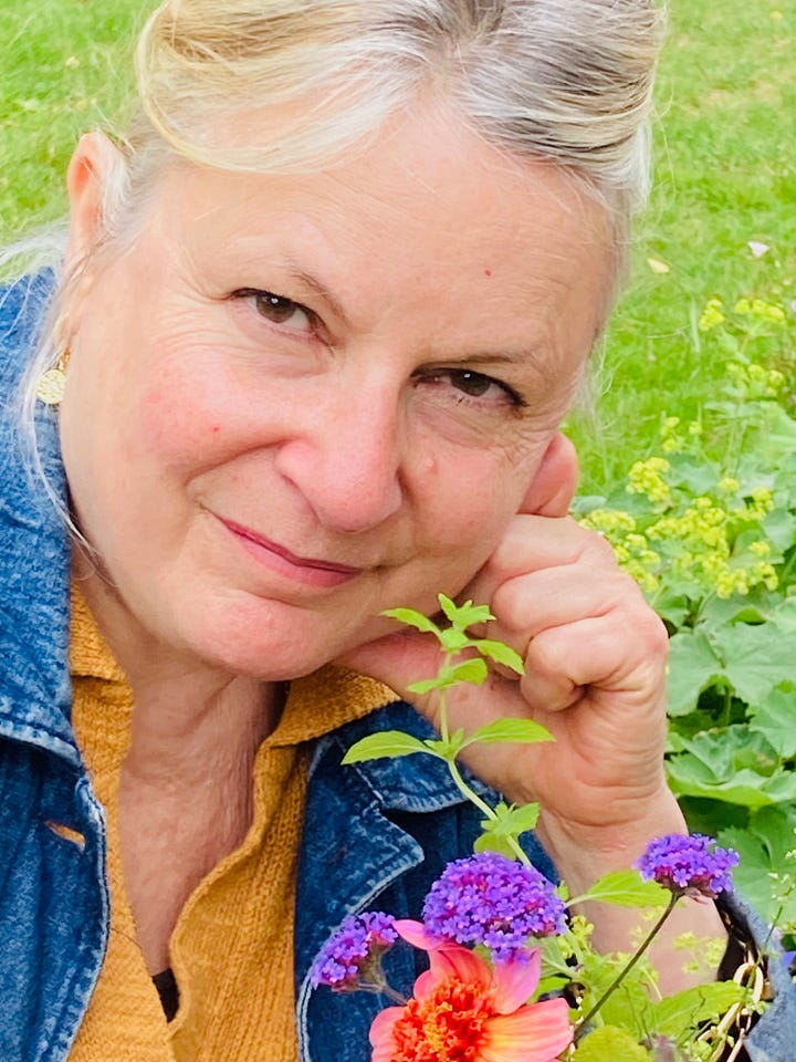 woman in garden looking at camera with purple flowers