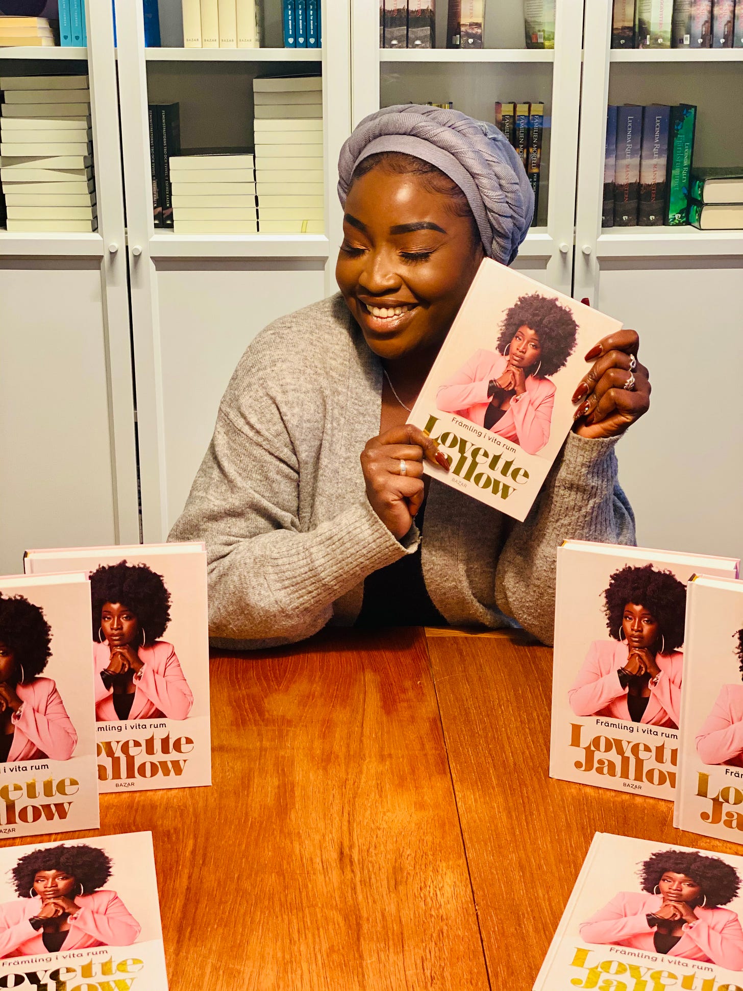 Lovette Jallow holding her book *Främling i Vita Rum* (Stranger in White Spaces), a groundbreaking work on race, neurodivergence, and systemic erasure in Sweden.