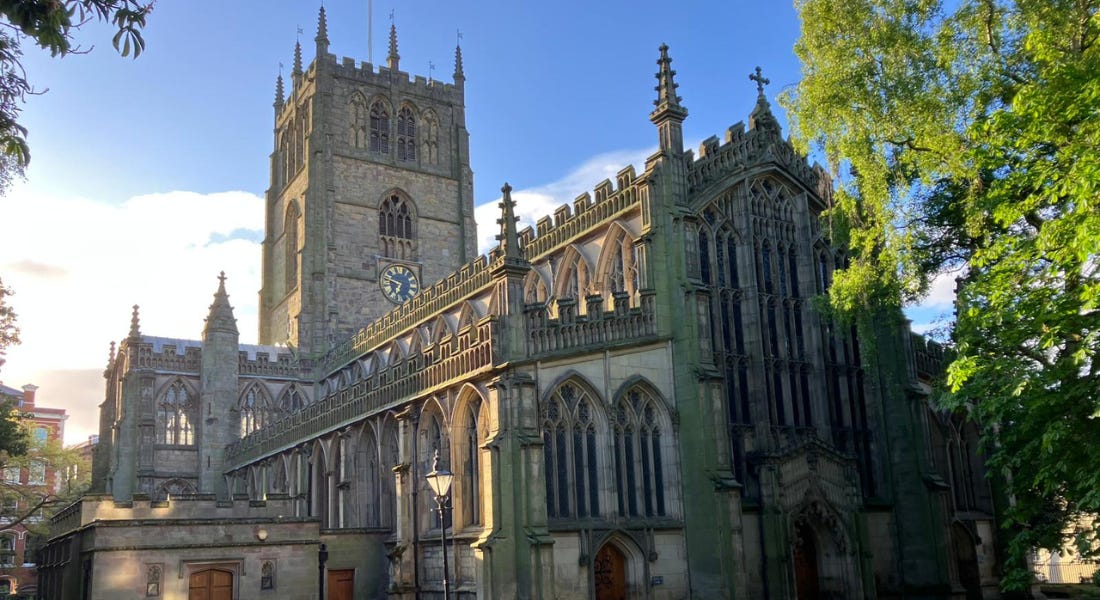 A sunny shot of a grey church - St Mary's Church in the Lace Market - with green foliage around it A sunny shot of a grey church - St Mary's Church in the Lace Market - with green foliage around it