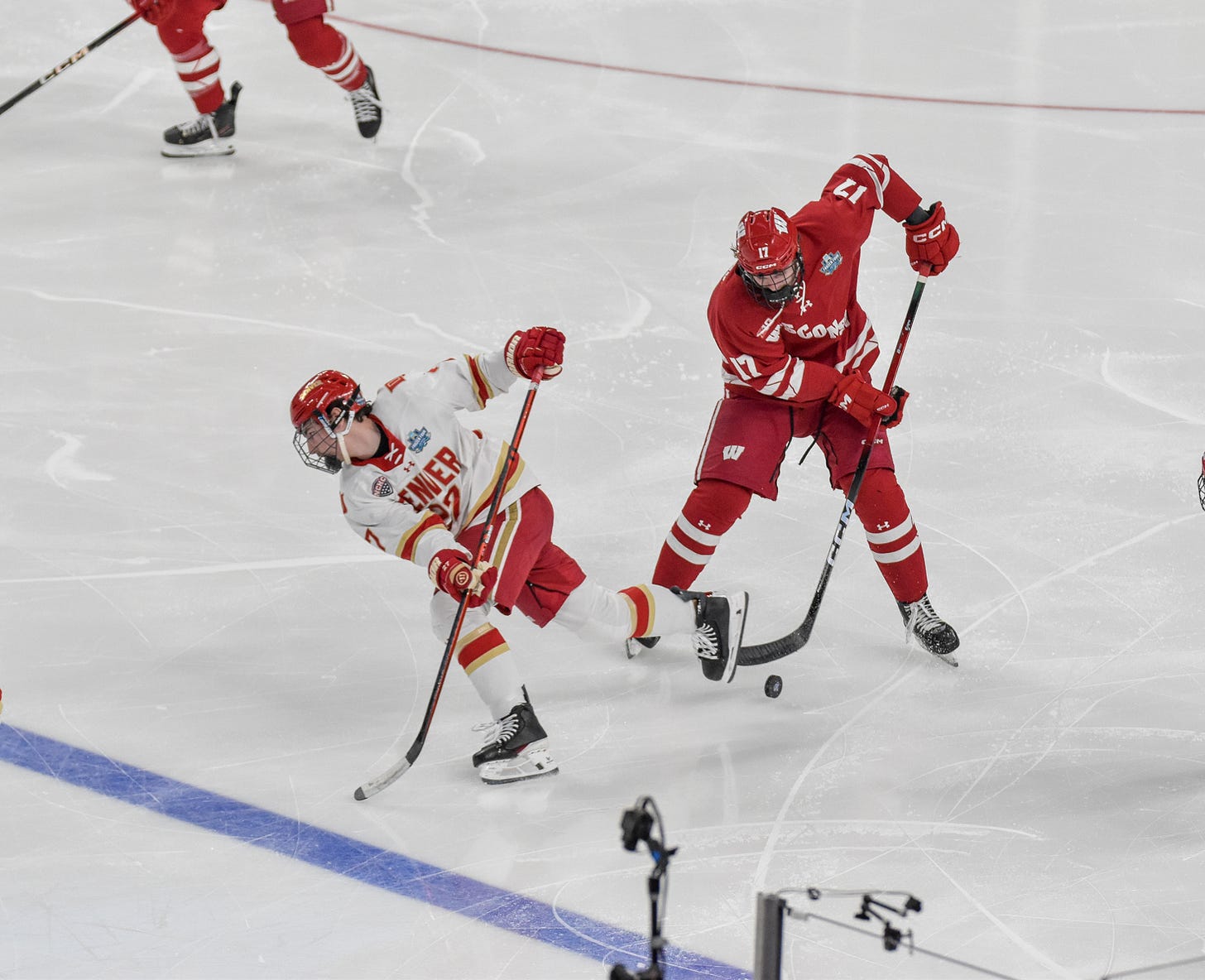 Wisconsin player Grady Deering looks down as puck bounces off ice with stick lowering to gain possession ahead in zone.