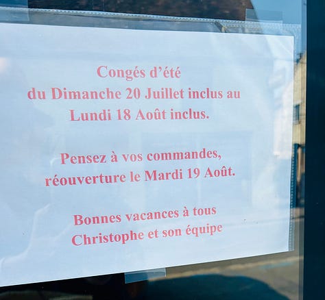 Two signs listing the dates of summer vacation closing times for businesses in France