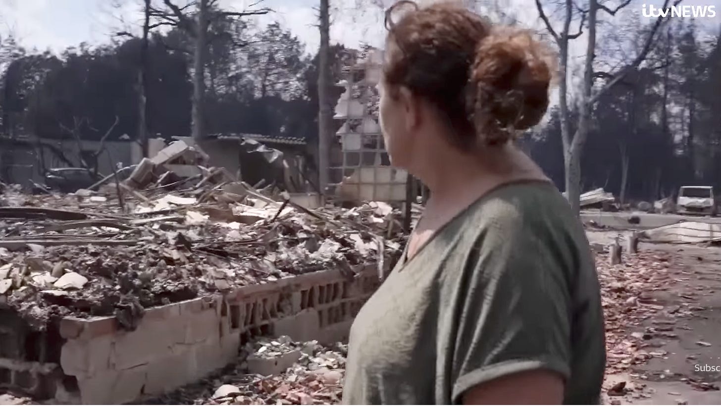 A middle-aged woman forlornly surveys the ruins of her home, burned down to the foundation.
