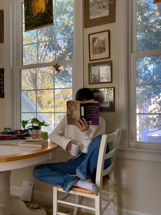 This may contain: a person sitting at a table reading a book