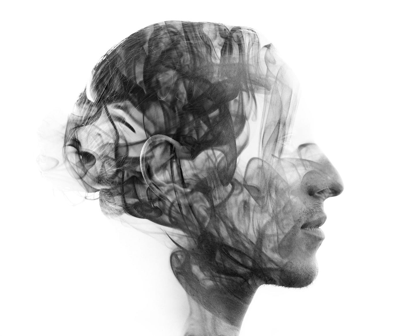 Double exposure portrait of a sexy statuesque man with dark features blending into a curtain of smoke