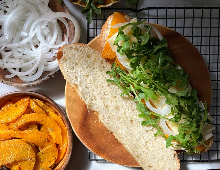 Hand holding hoagie roll, sandwich being assembled