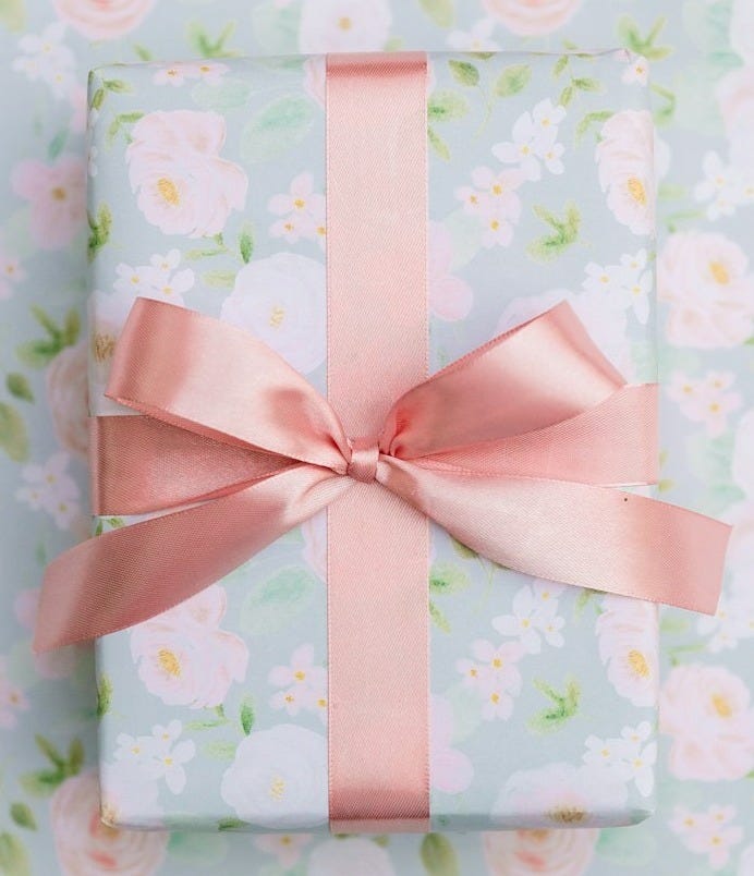 a present wrapped in pink ribbon on a floral background