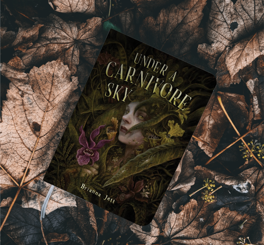 Book "Under a Carnivore Sky" on top of a bed of leaves Book "Under a Carnivore Sky" on top of a bed of leaves