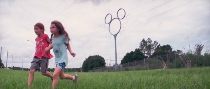 This may contain: two children are running in the grass near power lines