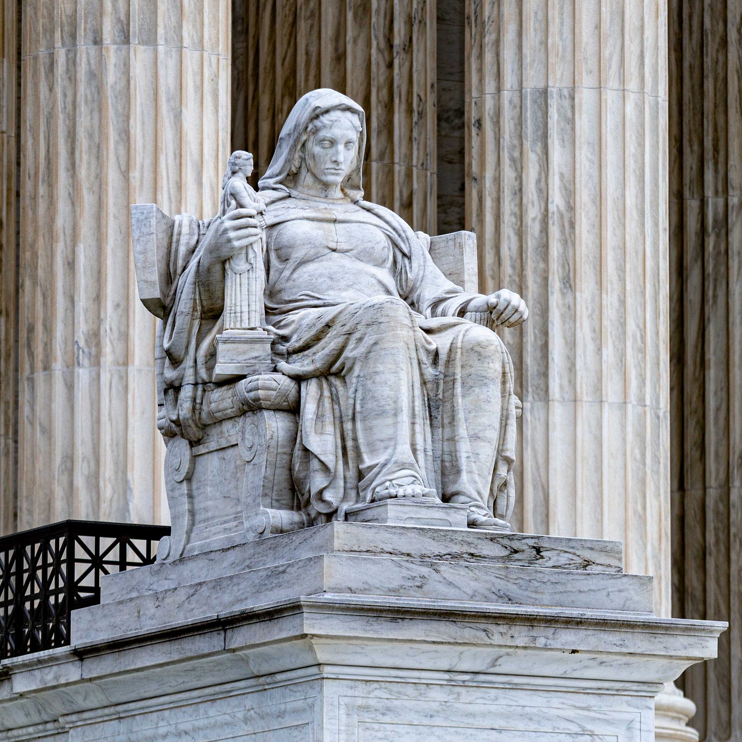 This unnamed figure, titled ‘Contemplation of Justice,’ sits in front of the  United States Supreme Court, holding the goddess Justice in her right hand, much like the infant depicted in front of the National Archive. One has to wonder if they are contemplating throwing Justice into the fire? Photo by Peter Duke ©2026 - All Rights Reserved