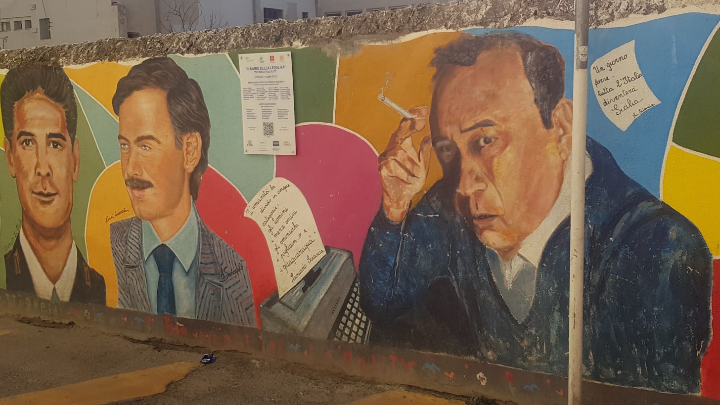 brightly coloured images of three men, one a writer, decorate a wall