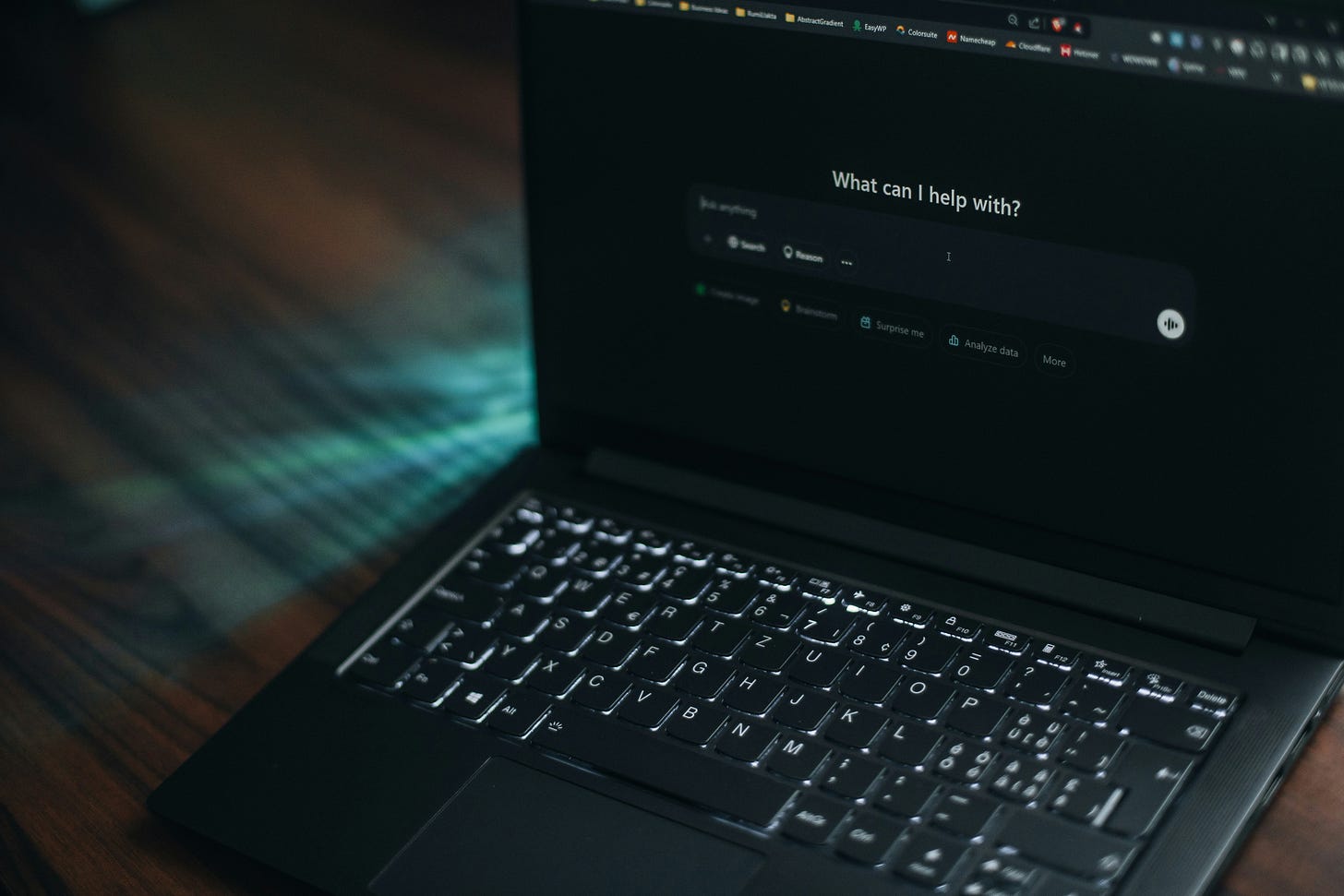 Dark laptop with a genAI tool on the screen asking "What can I help with?"