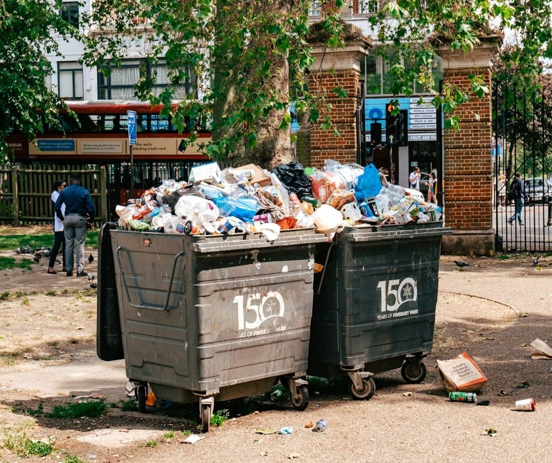 a couple of trash cans sitting on top of a sidewalk