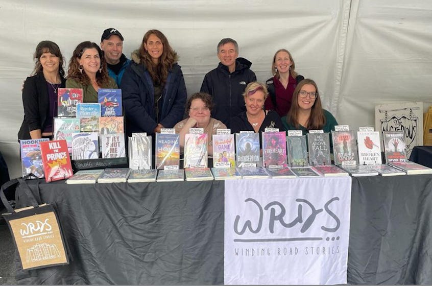 Photo of people standing behind a table full of books