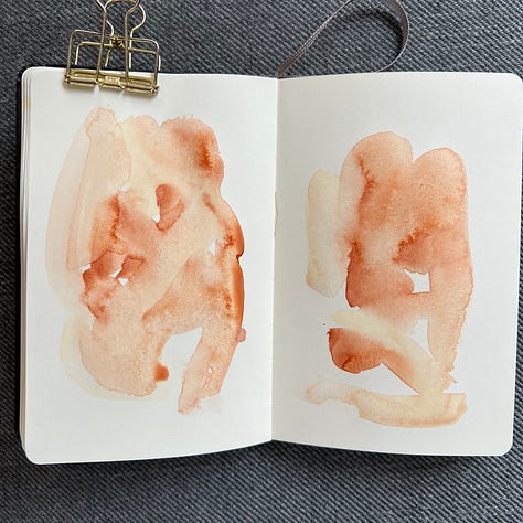 Different pages in a small sketchbook painted with light washes of watercolor in a variety colors