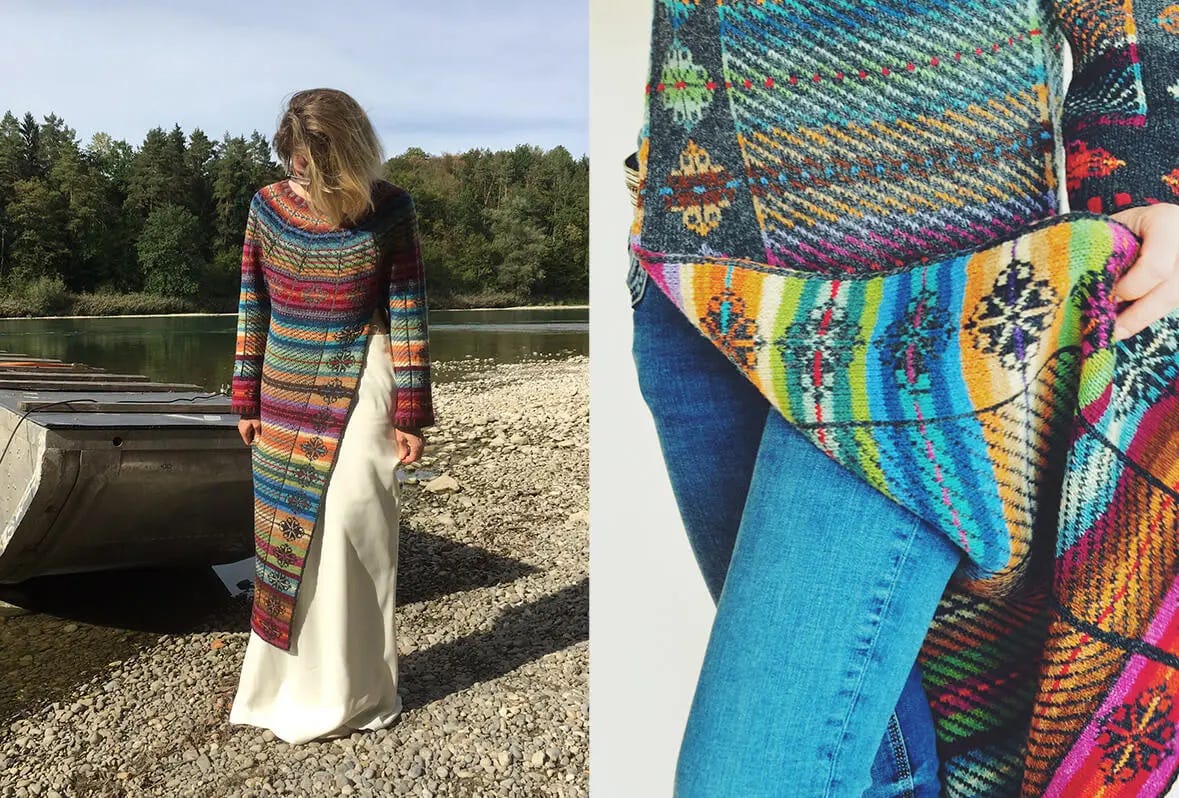 woman stands in front of a lake wearing a long colorful knitted coat in