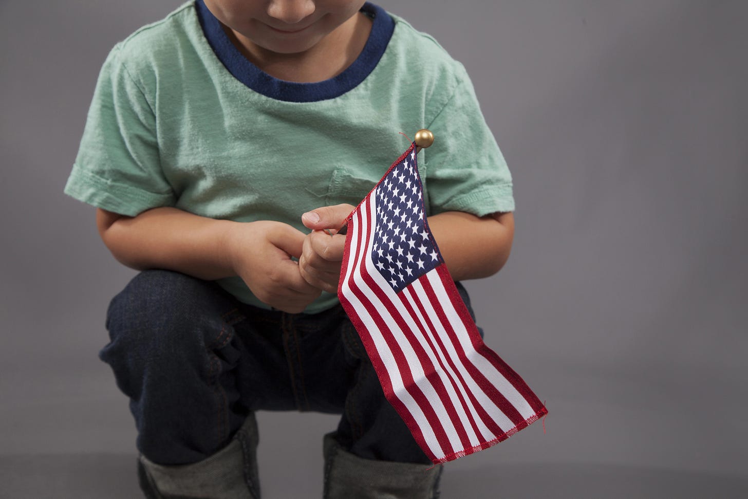 A small boy with a little US Flag in his hands.