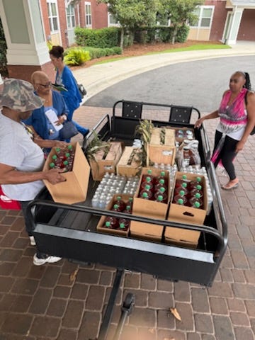 Citizens helping distribute food from a table and a truck trailer