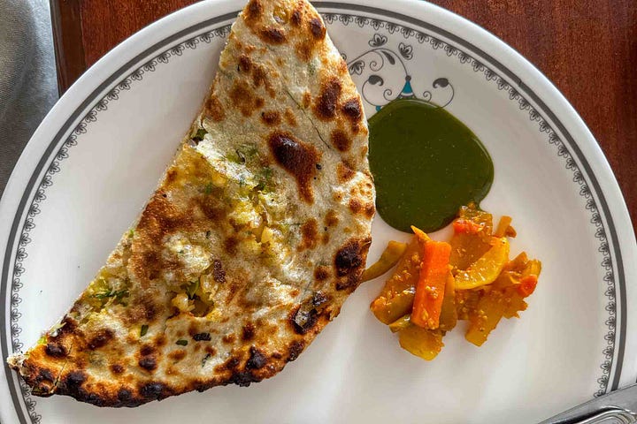 A mixed spread of vegetable pakoras and Amritsari kulcha with pickles and coriander mint chutney