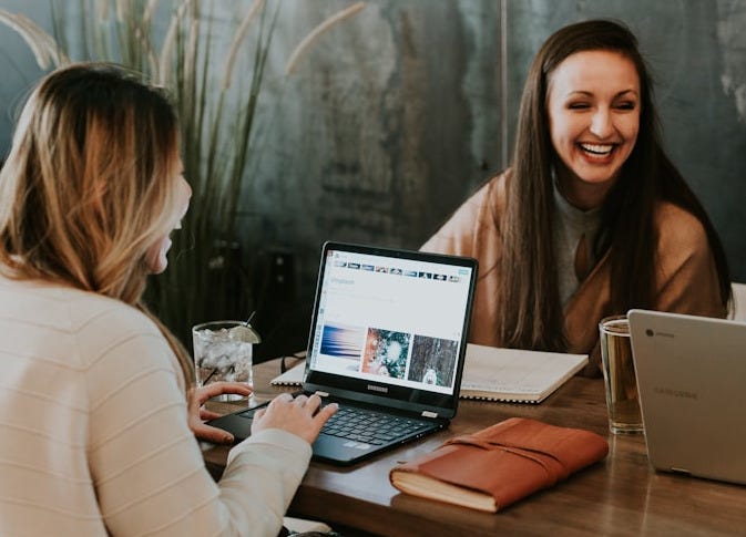 three people sitting in front of table laughing together three people sitting in front of table laughing together