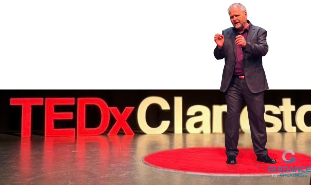 Salvucci gesturing and straining his face while delivering his TEDx speech. He stands on the iconic red dot and the TEDx lettering is visible behind him but the word Clarkstown is cut off.
