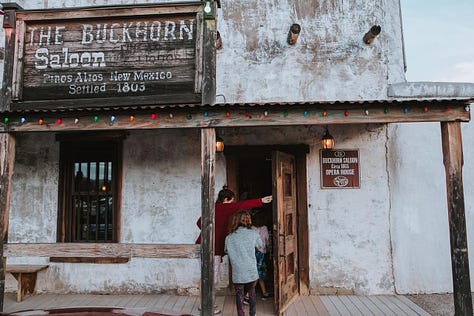 Whitesands National Park, an old saloon/opera house, pink architecture, cowboys eating pie in a cafe, Petroglyph on a boulder