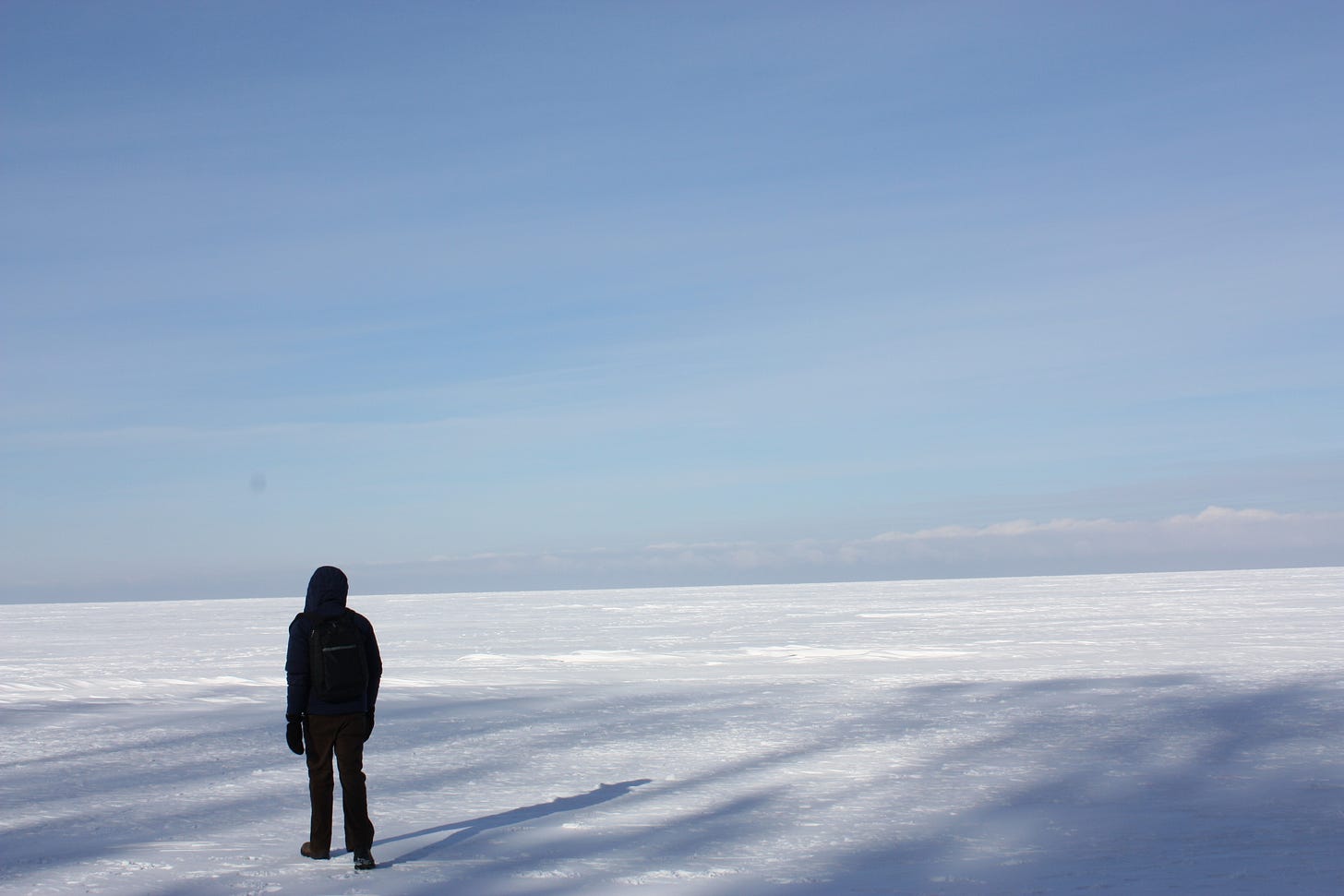 picture of man standing on giant field of ice under light blue sky