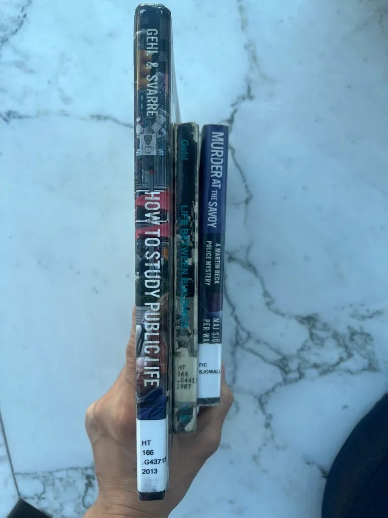 3 library books, being held by a hand so that the spines are visible. Texts on the spines: 1st book: Gehl & Svarre, How to Study Public Life. 2nd book: Gehl, Life Between Buildings. 3rd book: Murder at the Savoy: A Martin Beck Police Mystery, Maj Sjö Per Wa (the last names are covered up by a library label) 3 library books, being held by a hand so that the spines are visible. Texts on the spines: 1st book: Gehl & Svarre, How to Study Public Life. 2nd book: Gehl, Life Between Buildings. 3rd book: Murder at the Savoy: A Martin Beck Police Mystery, Maj Sjö Per Wa (the last names are covered up by a library label)