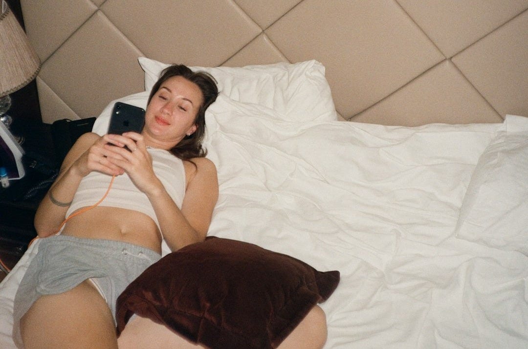 a woman laying in bed with a cell phone