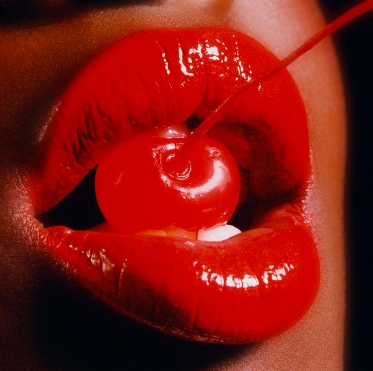 This may contain: a woman's lips with a cherry in the middle of her lip and an object sticking out of it