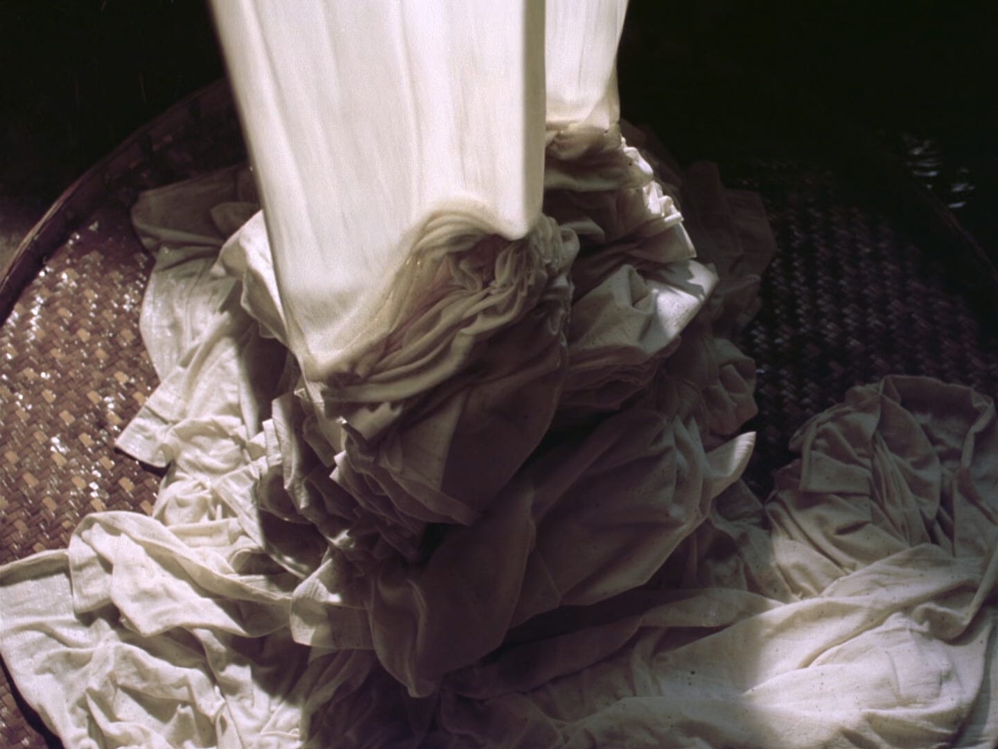 Wet white textiles pour onto a flat woven surface in "Ju Dou" (1990)