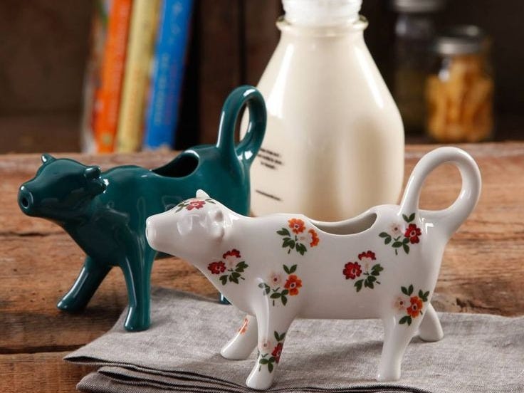 This may contain: two ceramic cow figurines sitting on top of a napkin next to a bottle of milk This may contain: two ceramic cow figurines sitting on top of a napkin next to a bottle of milk