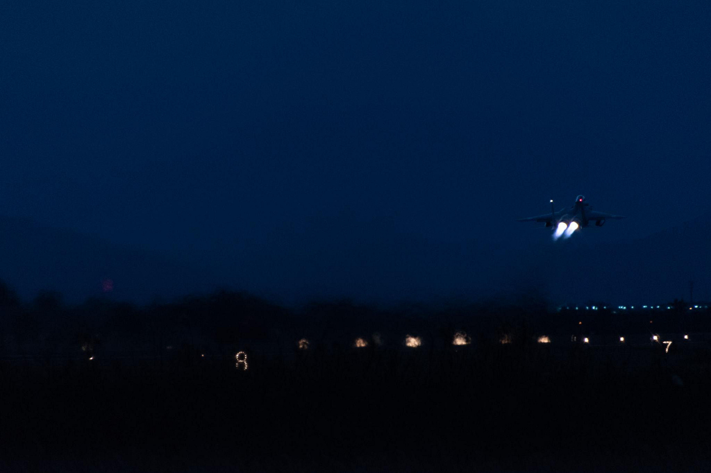 Jet fighter taking off at night.
