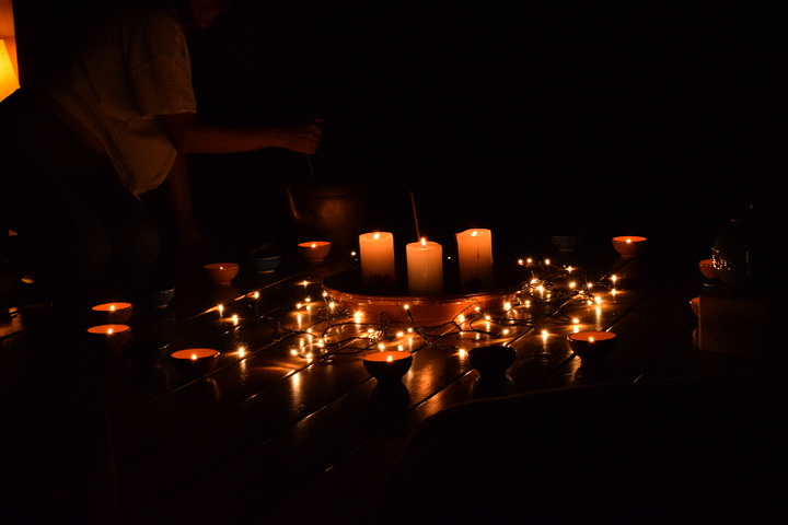 Four photos depicting candles at night, olive oil pouring from a spout, someone reading a book by the pool, and a field of flowers