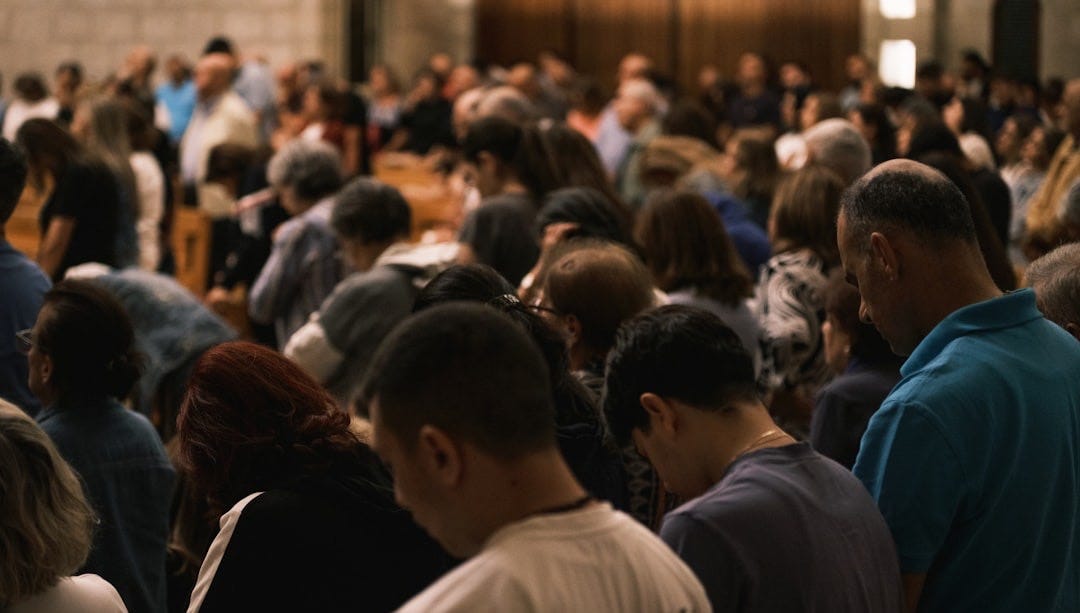 A crowd of people bowing their heads in prayer.